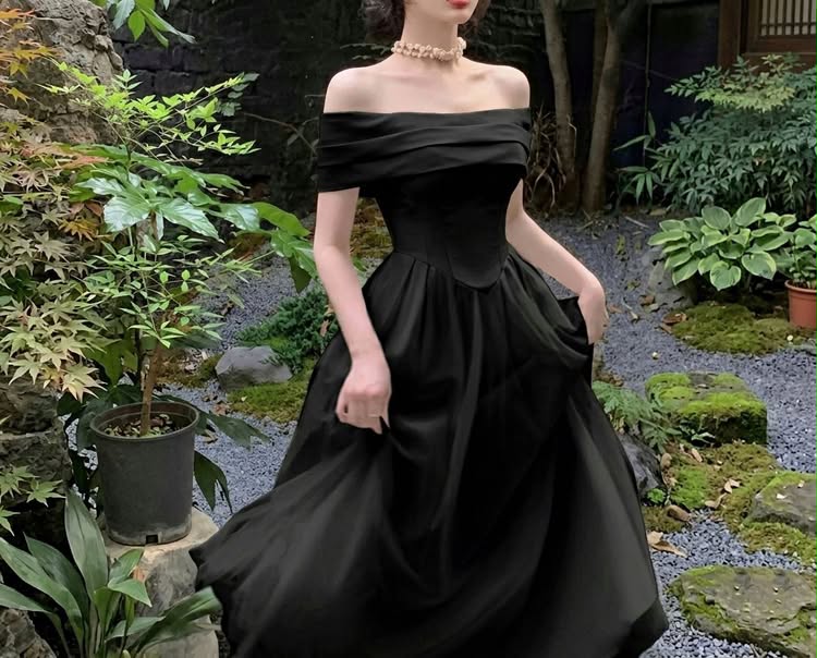 Elegant black off-shoulder dress styled in a serene garden environment, embodying a minimalist luxury aesthetic.